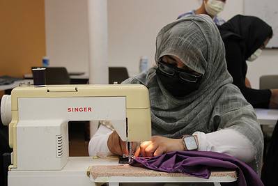 Afghan woman sewing at a sewing machine